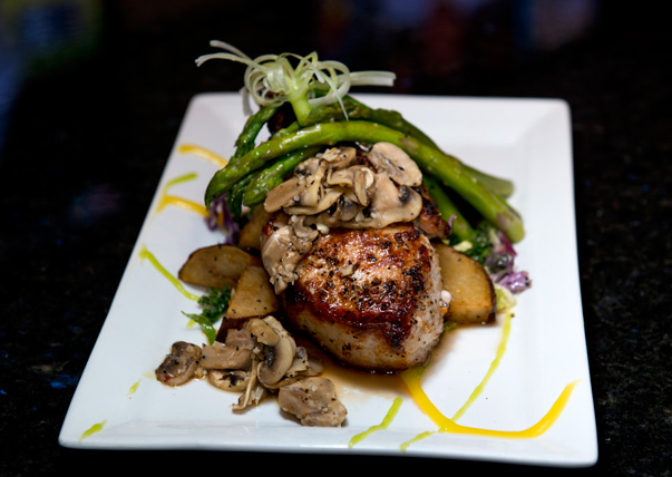 Grilled pork chop is topped with mushrooms and asparagus at Off The Cuff. photo by Natalie Green.