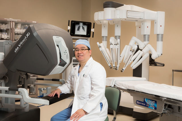 Dr. Peter Baik, a thoracic surgeon with CTCA sitting in a surgery suite with the Da Vinci Xi System.