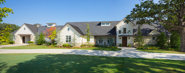 The exterior of this modern farmhouse features Buss Luders stone from Richburg Stone in downtown OKC. A board and batten style is used near the front door and complements the standing seam roof in a similar pattern.
