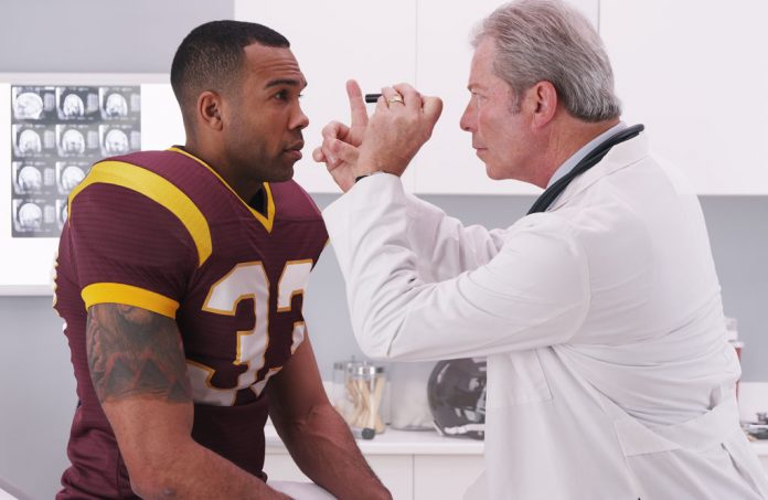 College football player having senior doctor review his concussi