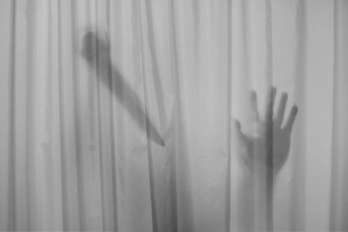 Horror Murderer. Dangerous man behind the frosted glass with a k