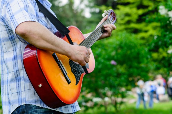man with a guitar in his hands outdoors