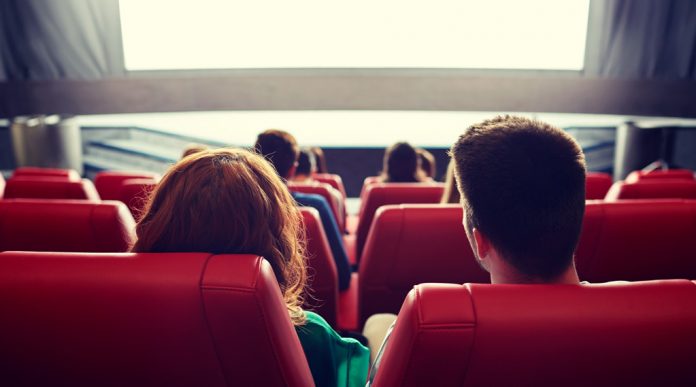 happy couple watching movie in theater or cinema
