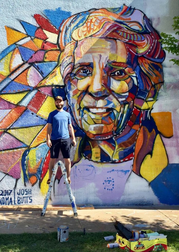 Mural artist Josh Butts takes a break in front of a work in progress.